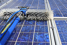 Solarmodule und Gerät zur Reinigung: Stiel mit Wasserschlauch und Stromkabel, vorne zwei Bürsten, mittig Spritzdüsen
