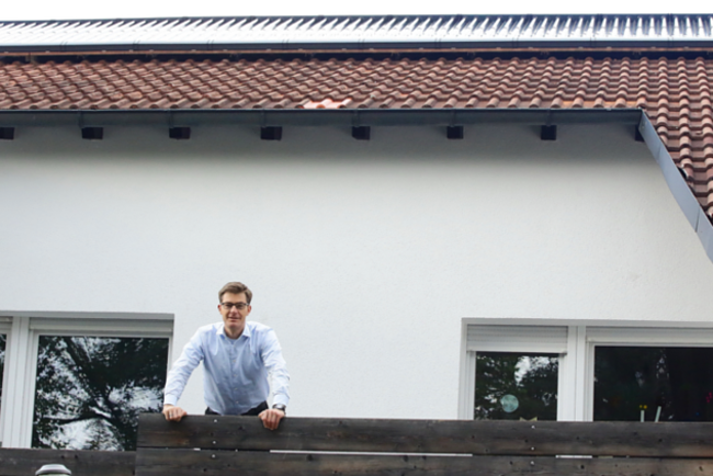 Christoph Kniehase auf seinem Balkob. Darüber befinden sich die Solarthermiekollektoren.