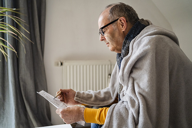 Senior man examining heating bill at home